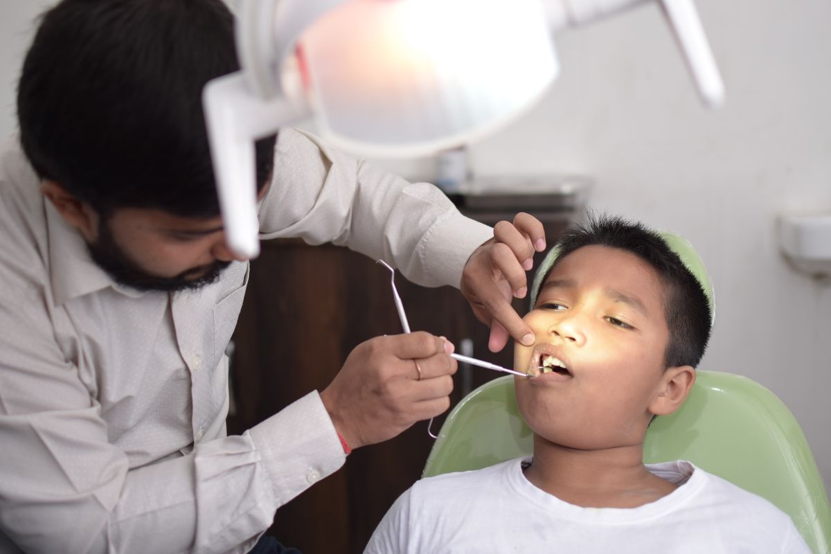 Dentista revisando la boca de un niño en la consulta