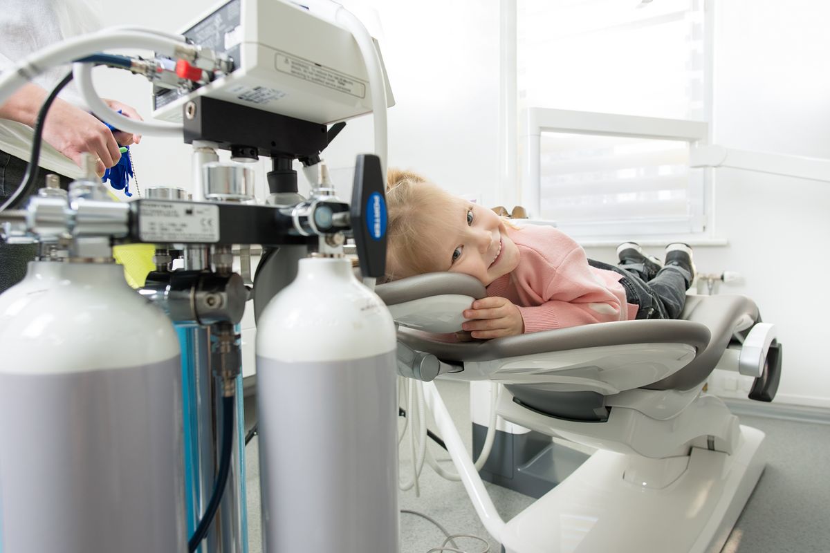 Niña tumbada en el sillón de la consulta dental