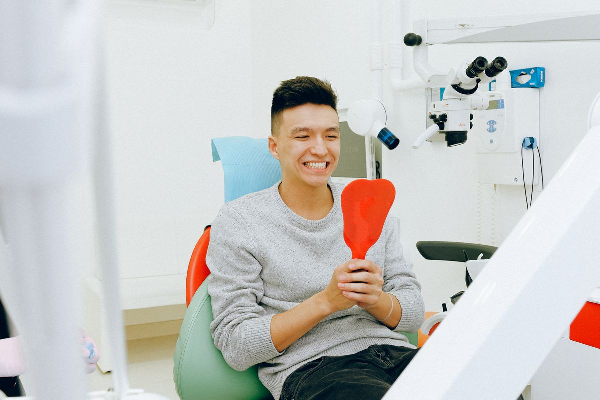 Hombre sonriendo con un espejo en la consulta dental