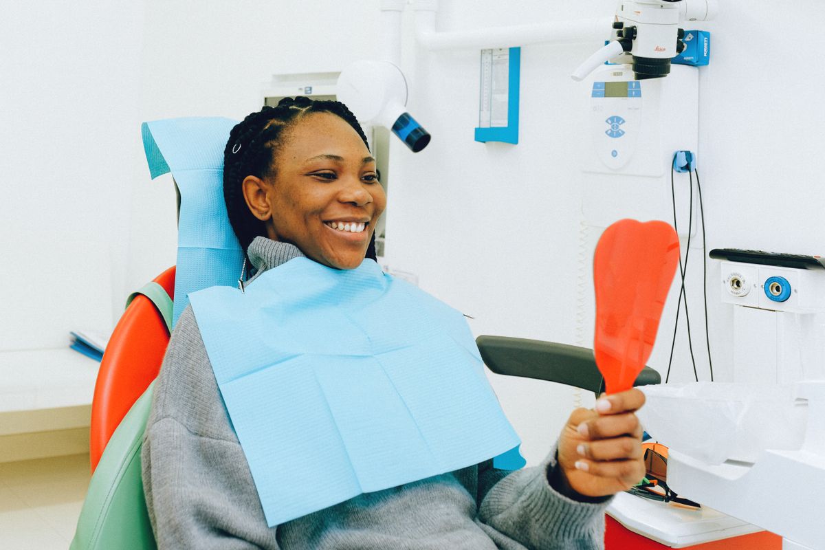 Paciente sonriente mirándose en un espejo tras su tratamiento dental
