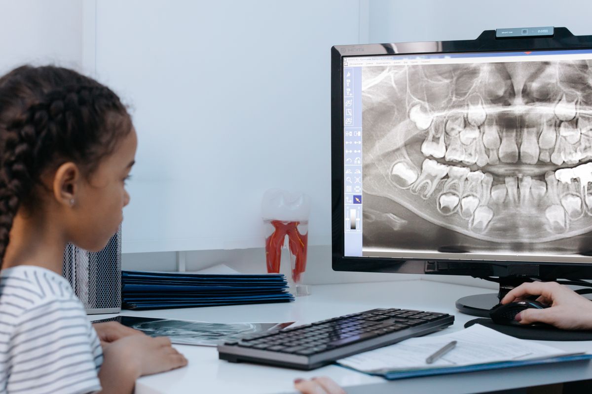Niña observando una radiografía dental en la pantalla